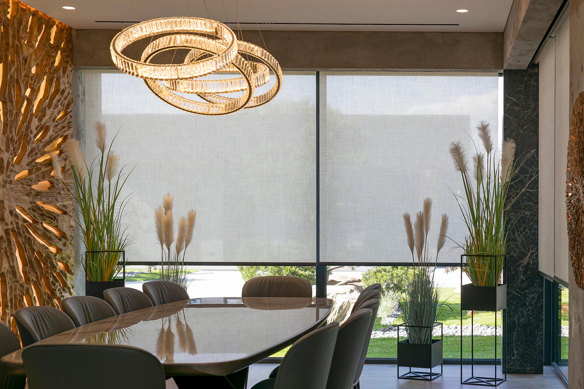 Dining room with modern chandelier, large windows, roller shades, and decorative plants